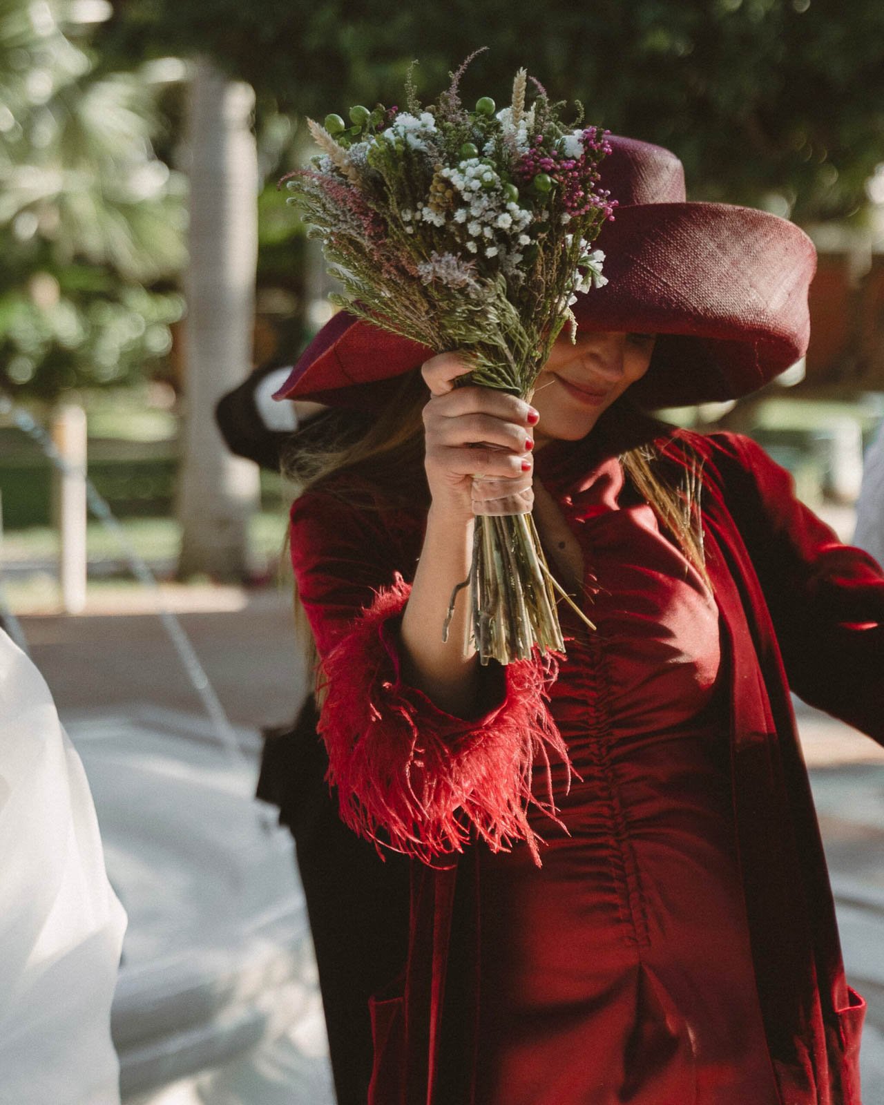 mujer de rojo sonriendo levantando un ramo