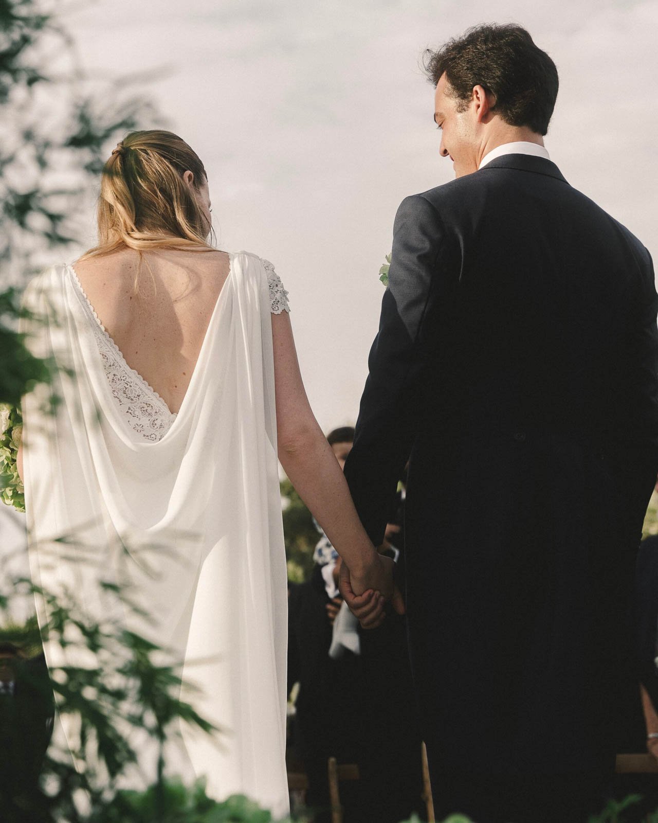 novios de espaldas avanzando entre la vegetación