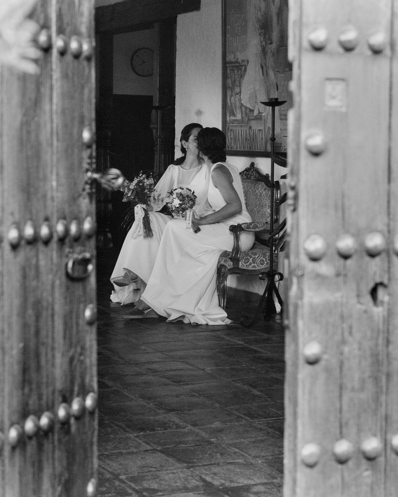 beso de novias sentadas tras una puerta