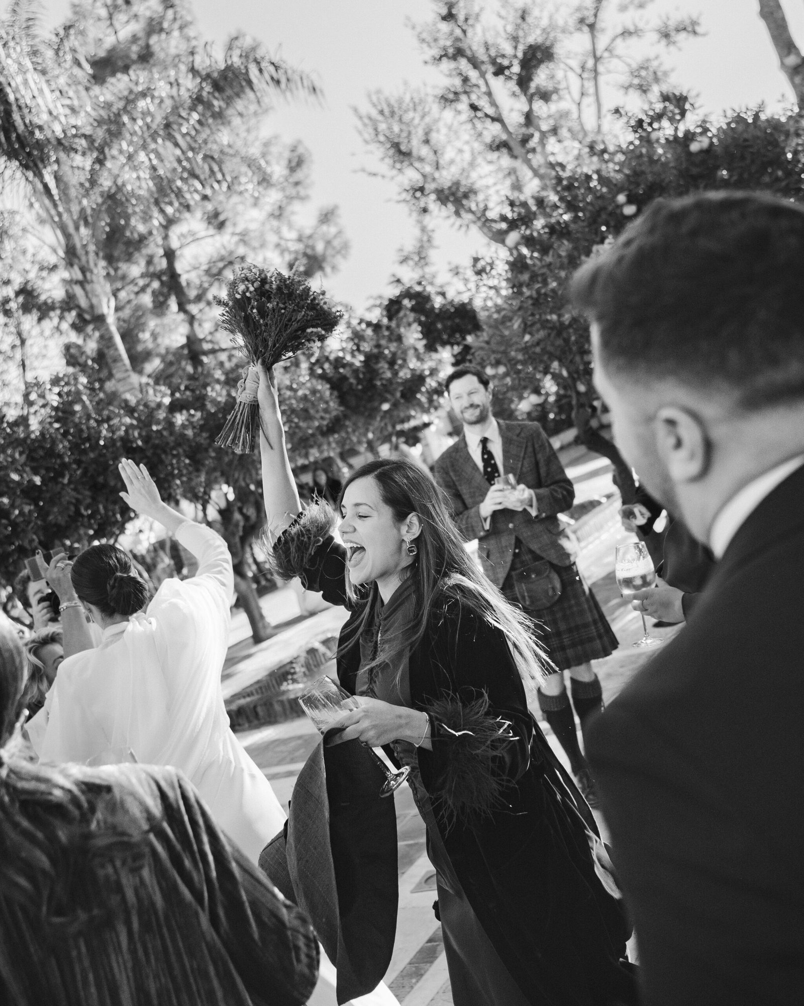 invitada de boda celebrando con ramo en alto