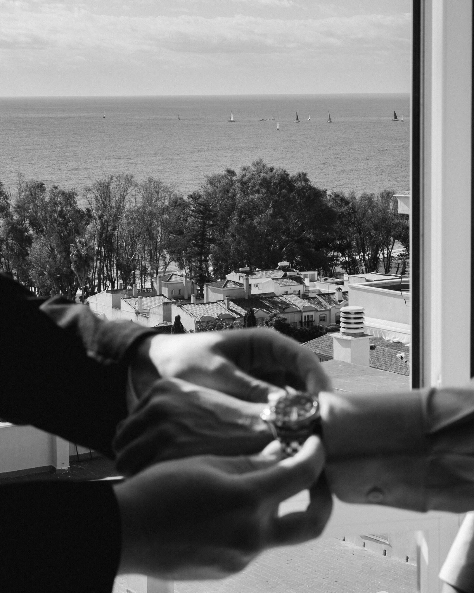 detalle de dos manos colocando un reloj con fondo de mar y barcos