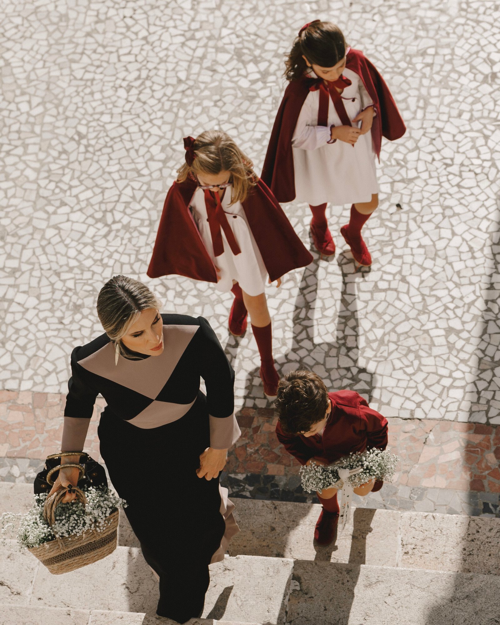 invitada de boda llevando decoración floral con niños pequeños acompañándola